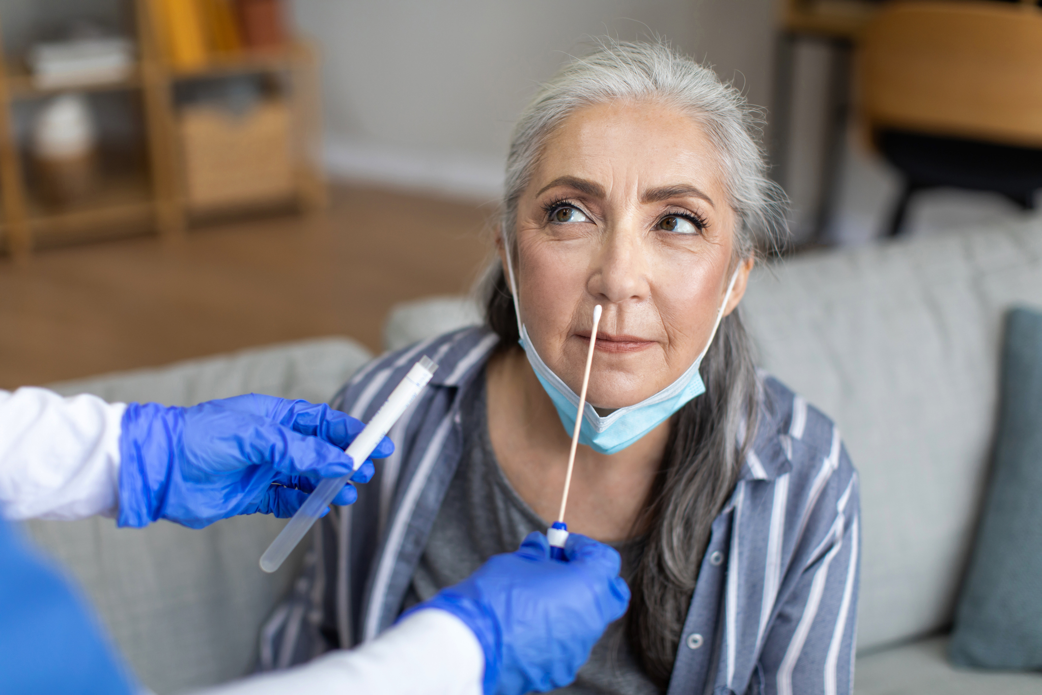 Enfermeiro realiza teste via swab nasal em uma mulher idosa na sua casa por causa do atendimento domiciliar